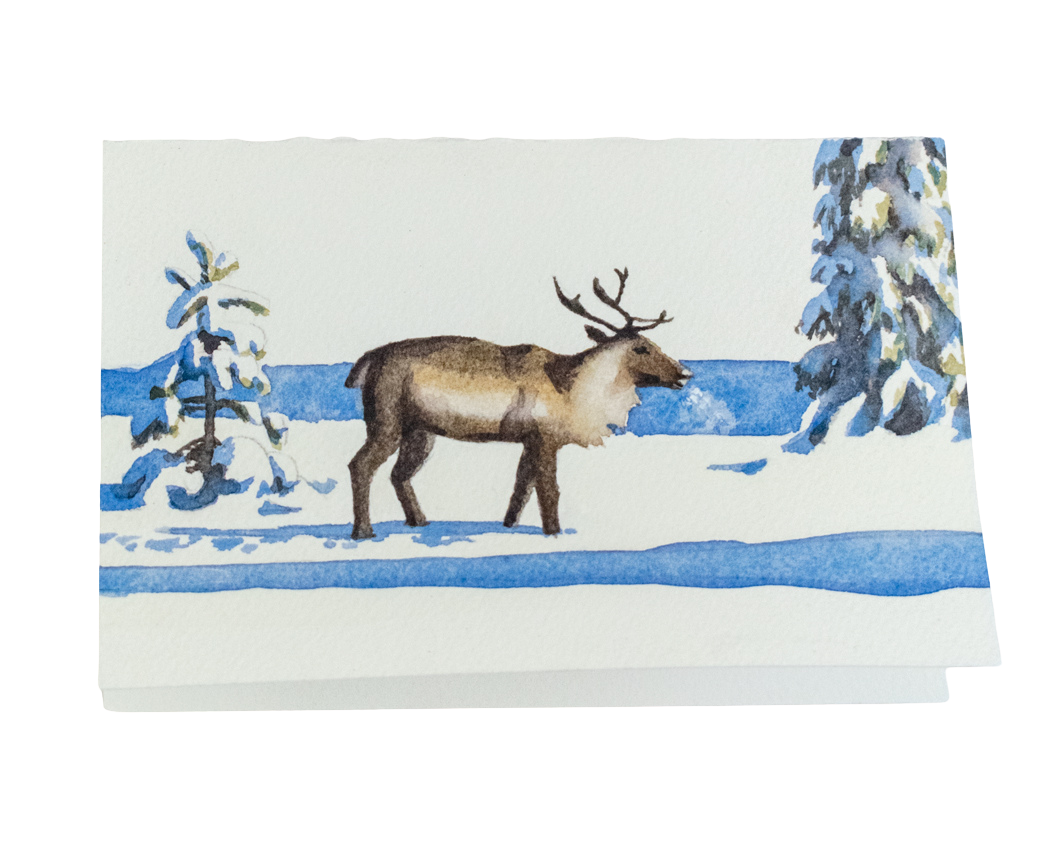 Carte de vœux peinte à la main représentant un renne marchant dans la neige au soleil et à côté d'épicéas couverts d'une épaisse couche de neige. L'ombre des arbres s'étend dans une couleur bleue vive et on voit la brume causée par le souffle du renne.